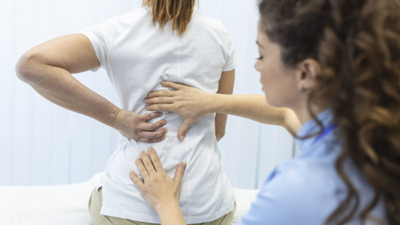 Physiotherapist doing healing treatment on womans back. Back pain patient, treatment, medical doctor, massage therapist.office syndrome